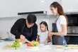 © atitaph - Happy family cooking together in the kitchen. Father, mother, and cute little daughter turn vegetables to make salads