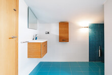 Wooden Furniture And Blue Tiled Floor In Modern Bathroom