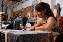 Focused Woman Using Sewing Machine In Workshop