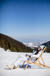 © BGStock72 - Young woman sitting at deck chair on ski track at the snowy mountain
