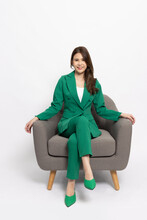 Attractive Beautiful Young Asian Business Woman In Green Suit Sitting On Armchair Isolated On White Background