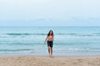© machirito - Very long shot of a teenager coming out of the sea in summer after a swim.