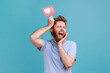 © khosrork - Portrait of excited bearded man holding like counter button, smiling with pleasure, rejoicing and amusing with popularity on internet, social network. Indoor studio shot isolated on blue background.