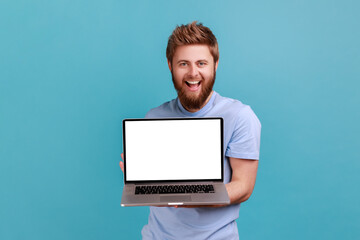 Wall Mural - portrait of bearded man holding and showing laptop with blank empty display, place for your advertis