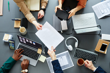 High angle view of team of programmers developing new software for virtual reality glasses sitting at table at meeting