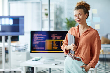 portrait of young female programmer with digital tablet looking at camera while standing at her work