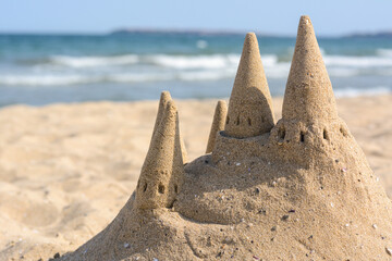 Canvas Print - Beach with sand castle near sea on sunny day. Space for text