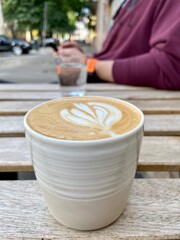 A cup of cappuccino on a wooden table in a coffee shop by the road. Stop for a coffee break. 