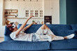 © Friends Stock - Young Asian guy wearing VR glasses and lying on sofa at his appartment