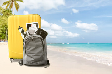 suitcase and backpack with beach accessories on sand. travel concept