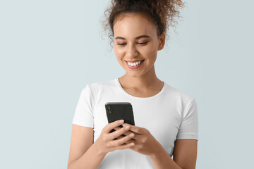 Sticker - Female African-American tourist using mobile phone on light background