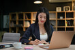 © bongkarn - Attractive young-adult Asian businesswoman is focused on her task at the office desk.