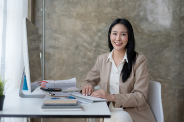 Wall Mural - Charming Asian business woman have a happy of working laptop at the office. Looking at camera.