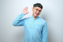 Young Handsome Asian Man Waiving Saying Hello Happy And Smiling, Friendly Welcome Gesture