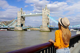 Fototapeta Londyn - Tourist girl leaning on the railing on River Thames promenade with Tower Bridge famous landmark in London, UK