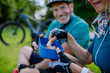 © Halfpoint - Active senior couple resting after bicycle ride at summer park, sitting on grass and having snack. Close-up.
