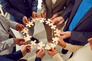 Wall Mural - Creative business team finds a solution to the problem. Group of multiracial people form a circle from different pieces of wooden jigsaw puzzle. Teamwork concept. Cropped shot. Conceptual background