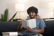 © zinkevych - Curly-haired indian guy reading a book and looking involved
