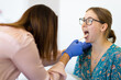© Austockphoto - Young female with mouth open being checked by doctor