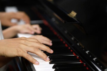 Select the focus on the piano trainer fingers and piano keys to play the piano. There are musical instruments for concerts or music lessons. Close-up of child musicians playing piano on stage