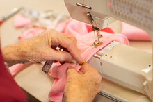 Lady's Hands Measuring Hem On Garment She Is Sewing