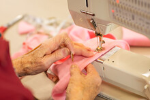 Hands Of Elderly Person Guiding Fabric On Sewing Machine