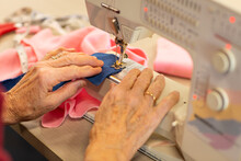 Hands Of Woman Guiding Fabric Through Sewing Machine