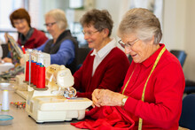 Group Of Older Ladies Sewing With Machines