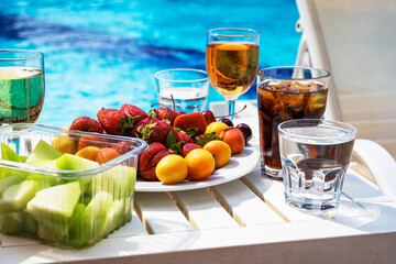 Fruit plate and drinks on the background of the hotel pool. All inclusive.