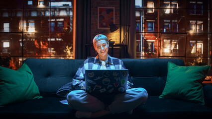 Fototapete - Young Attractive Woman Working from Home on Laptop Computer with Stickers in Cozy Stylish Loft Apartment. Creative Female Smiling, Checking Social Media, Browsing Internet. Flat with Big Windows.