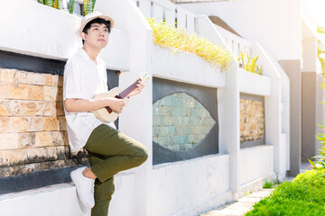 Wall Mural - Asian man with hat playing guitar ukulele