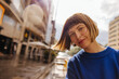 Close-up of young pretty caucasian girl peeking into camera being outdoors. Brown-haired woman with bob haircut wears blue sweatshirt. Lifestyle, different emotions, leisure concept.
