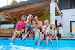 © Halfpoint - Multi generation family enjoying drinks when sitting at backyard pool.