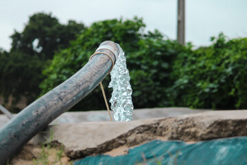 Water from a well filled a pond for irrigation,Pump pipe water flow equipment agriculture,Water from a well filled a pond for irrigation,farming concept,selective focus