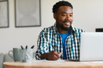 Wall Mural - happy african american man using laptop working online at home