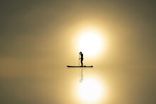 Man Stands In A Boat And Floats On Calm Water With Reflection