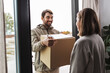© Syda Productions - shipping, transportation and people concept - delivery man with parcel box and clipboard talking to customer at home