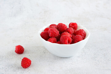 heap of fresh garden raspberries in white bowl isolated, close-up