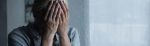 Depressed Blonde Woman Covering Face Behind Wet Window With Rain Drops, Banner.