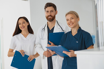 Wall Mural - Portrait of a group of happy and successful doctors and nurses standing near reception in hospital