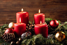 Four Burning Red Advent Candles In Advent Wreath Decoration On Wooden Dark Background. Tradition In Time Before Christmas. Xmas Lights With Christmas Fir Deco Background Concept. Festive Still Life.