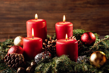 four burning Red advent candles in advent wreath decoration on wooden dark background. tradition in time before Christmas. xmas lights with christmas fir deco background concept. Festive still life.