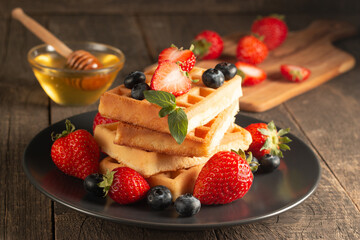 fresh homemade food of berry belgian waffles with honey, chocolate, strawberry, blueberry, maple syr