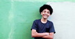 © Marco - Happy mixed race child smiling at camera leaning on wall with arms crossed