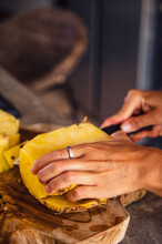 Woman Cutting Pineapple In Kitchen