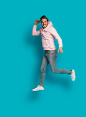 Wall Mural - Full size photo of young happy excited smiling positive man jumping isolated on light blue color background.