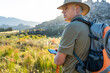 Mature hiker looking away while using smartphone navigator