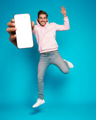 Wall Mural - handsome excited man showing pointing at empty smartphone screen posing over light blue background, 