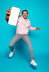 Wall Mural - handsome excited man showing pointing at empty smartphone screen posing over light blue background, 