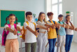 © Studio Romantic - Group of students in classroom show their thumbs up to show their approval of great choice. Preteen boys and girls with backpacks on their shoulders stand in row and smile at camera. Education concept